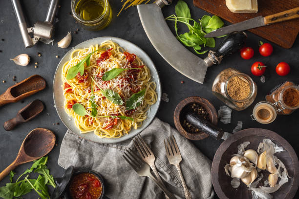 istock Italian dinner with pasta on ceramic plate with ingredients around on black background. Flat view. Top view. 1275876186