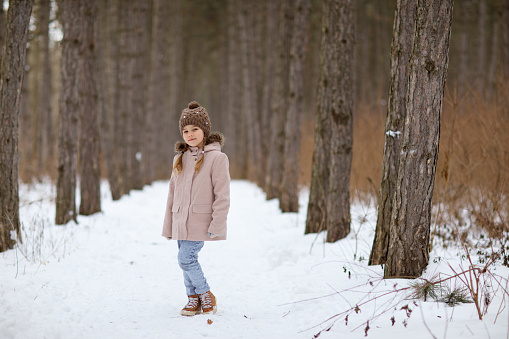 a little girl in a snowy winter forest. travel and recreation with children in winter. walking in the fresh air during the new year holidays.
