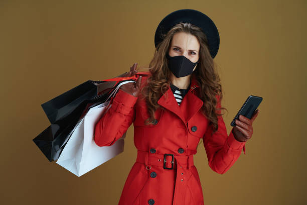 istock trendy woman using phone app isolated on bronze background 1275879246