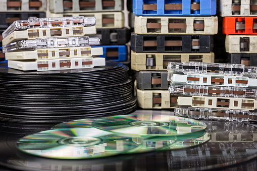 A collection of audio music including 8-track tapes, cassette tapes, vinyl 33 rpm LP record albums, 45 rpm single records, and compact discs.