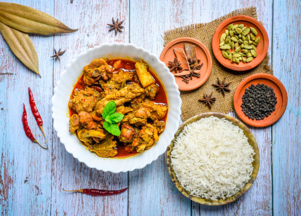 istock Chicken curry or masala , spicy reddish chicken leg piece dish garnished with coriander leaf and arranged in a white ceramic bowl with wooden background 1275880284