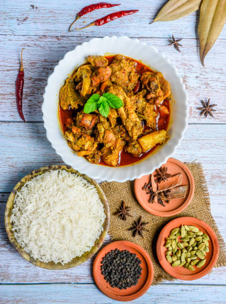 istock Chicken curry or masala , spicy reddish chicken leg piece dish garnished with coriander leaf and arranged in a white ceramic bowl with wooden background 1275880326