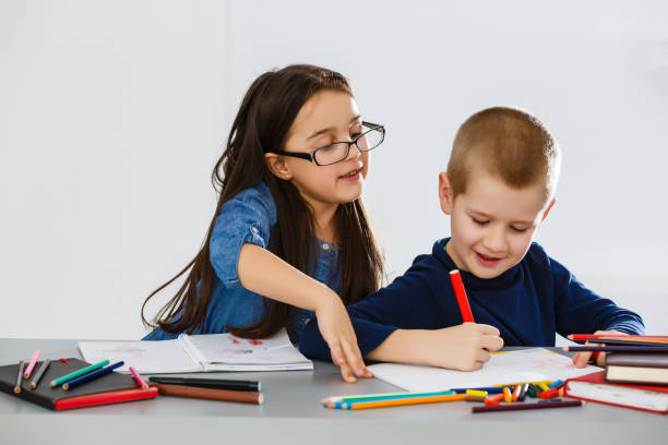istock Two smiling little kids at the table draw with crayons, isolated on white 1275881489