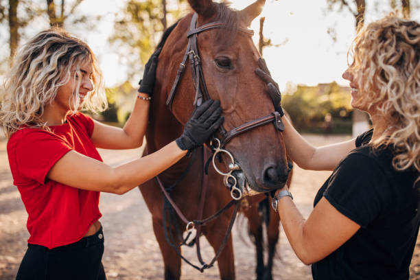 istock Two cheerful women cuddle horse at farm 1275882362