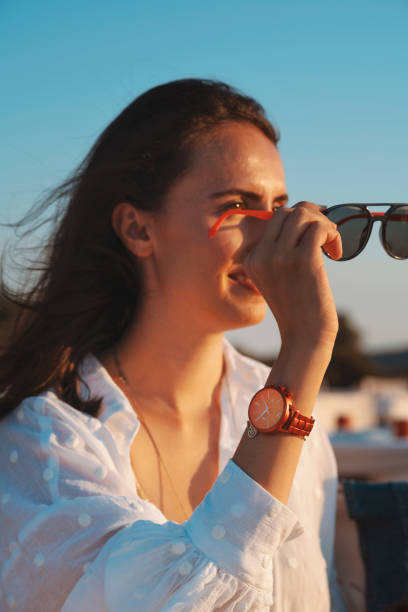 istock Young woman wearing sunglasses looking at sunset 1275884830
