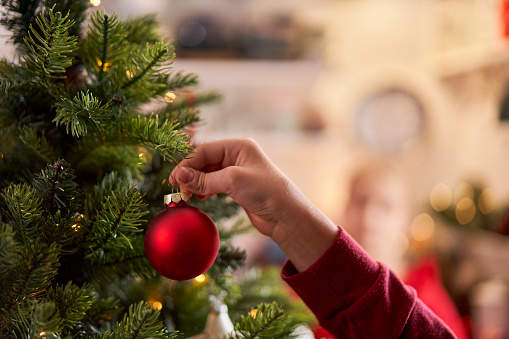 Cute Little Girl Decorating Christmas Tree with Ornaments and Christmas Lights