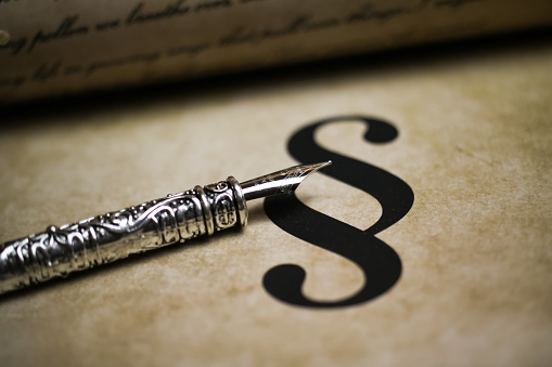 Closeup of isolated paragraph sign on ol vintage paper with silver retro ink pen and text document (focus on ink pen tip, text is self-made)