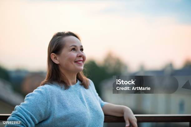 Mature Woman Looking Optimistic On The Future Over Evening Sky Stock Photo - Download Image Now