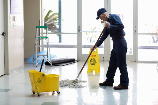 Senior Adult Janitor mops floor at entry to offices. Senior adult Janitor keeps the floors cleaned and sanitized due to the virus. caretaker stock pictures, royalty-free photos & images