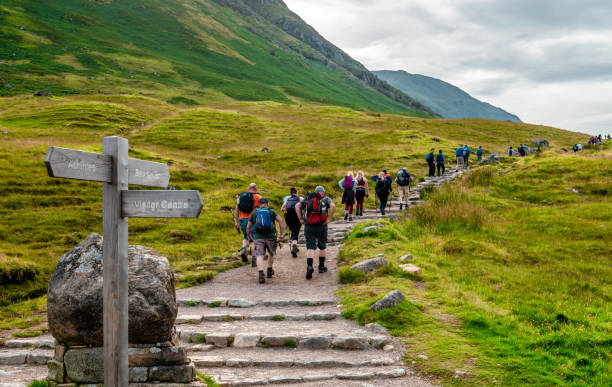 Hiking Ben Nevis in Summer. This is the starting point of the Mountain Path, the most popular route of ascent. The path starts at Achintee, around 2km south-east of Fort William, in the Scottish Highlands. Achintee / UK - August 24 2019: Ben Nevis is the highest mountain in Britain. The Mountain Track to the summit (also known as the Ben Path, the Pony Track or the Tourist Route) remains the simplest and most popular route of ascent. It begins at Achintee on the east side of Glen Nevis about 2 km (1.5 miles) from Fort William town centre, at around 20 metres above sea level. lochaber stock pictures, royalty-free photos & images