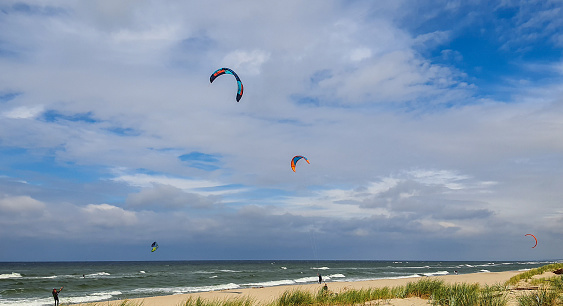 People go kitesurfing on the seaside on a cloudy day in stormy weather.