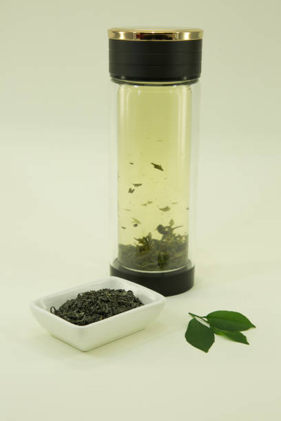 Chinese green tea. Green tea from Beijing. Lemon leaf. Tea from Beijing is brewed in a double glass thermo dish. Isolated in a white bowl on a white background