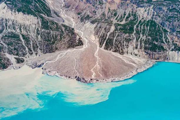Photo of A river delta is a landform created by deposition of sediment that is carried by a river as the flow leaves its mouth and enters slower-moving or stagnant water.  Flight over Glacier Bay National Park, Alaska. Alluvial fan delta.