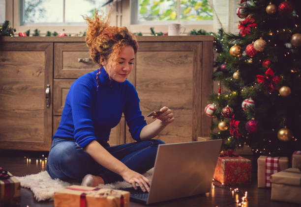 istock Young Beautiful Woman Enjoying at Home in a Cozy Christmas Atmosphere While Using Lap Top for Online Shopping. 1276004972