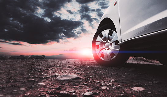 Closed image of car wheels and tires on the ground and sunset sky