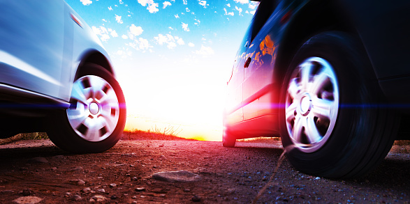 Closed image of car wheels and tires on the ground and sunset sky
