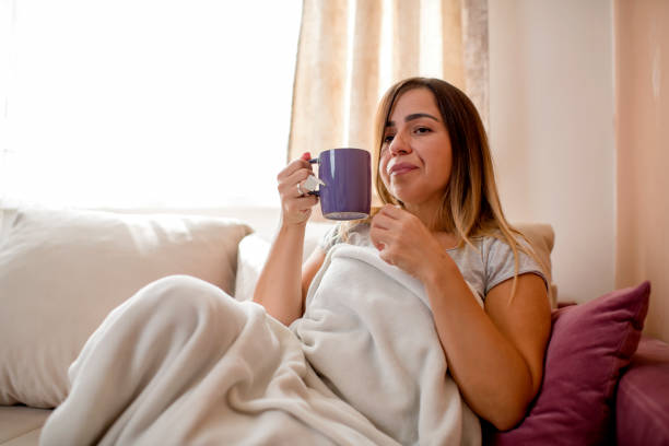 istock Young woman with cup, sitting at home on sofa 1276045539