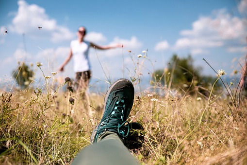 Female hiker sport shoes relaxing after trakking. Hiking boots in grass and Young Female enjoying on meadow