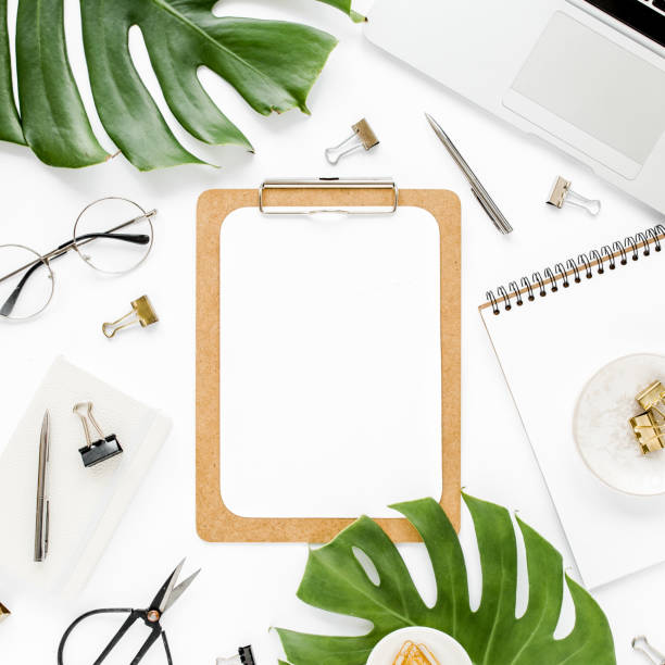 istock Home office workspace mockup with laptop, tropical leaves Monstera, clipboard, notebook and accessories on white background. Flat lay, top view 1276067338