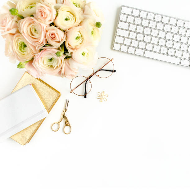 istock Stylized women's home office desk. Workspace with computer, bouquet ranunculus and roses, clipboard on white background. Flat lay. Top view 1276084668