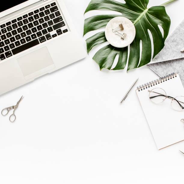 istock Home office workspace mockup with laptop, tropical leaves Monstera, clipboard, notebook and accessories on white background. Flat lay, top view 1276085816