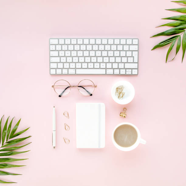 istock Office table desk with computer, green leaves palm, clipboard. Top view. Flat lay. Home office workspace. Women's accessories on pink background 1276088754