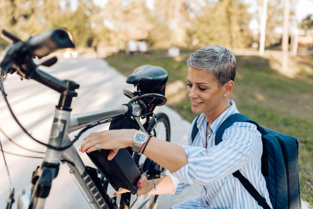 仕事に行く途中で彼女の電動自転車を充電する幸せな女性 - short cycle ストックフォトと画像