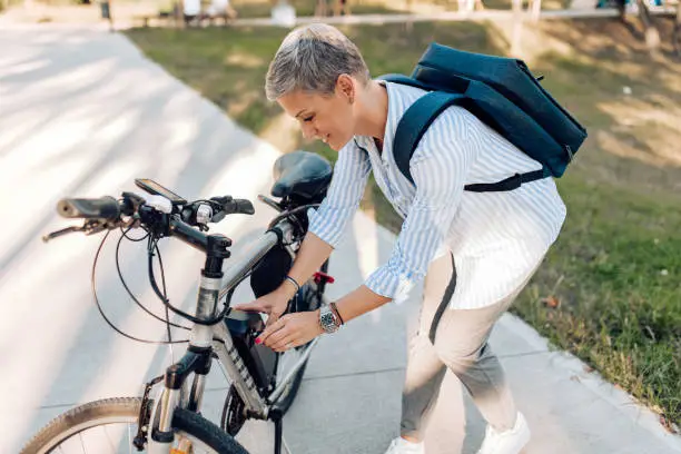 Mid adult woman charging her electric bicycle on her way to work.