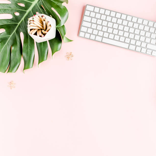 istock Flat lay home office desk. Female workspace with computer, tropical palm leaves Monstera, accessories on pink background. Top view background 1276093249