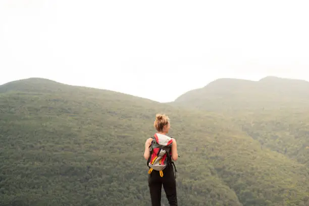 A young woman hiking alone through mountains with a backpack.