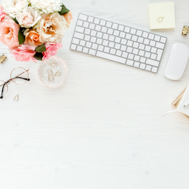 istock Flat lay women's office desk. Female workspace with computer, pink roses flowers, accessories, golden diary, glasses on white background. Top view 1276093434