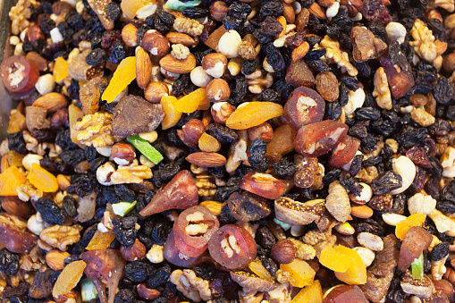 Top view of wooden bowls with dried fruit, berries and nuts as ingredient for tasty and healthy meal on grey concrete background