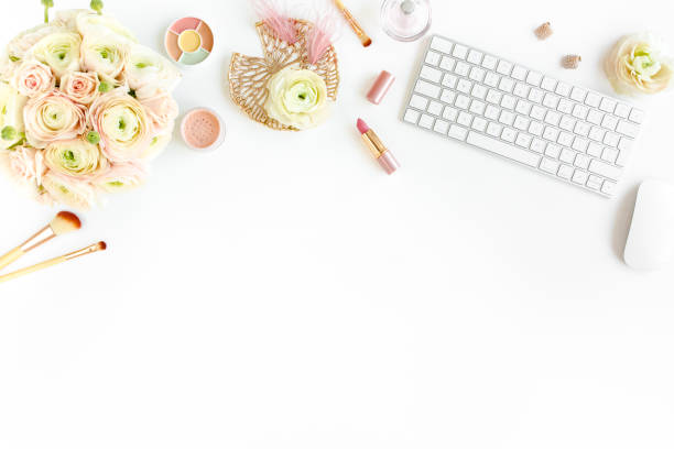 istock Stylized women's home office desk. Workspace with computer, bouquet ranunculus and roses, clipboard on white background. Flat lay. Top view 1276097114