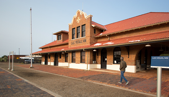 Las Vegas, NM: Man walking at the historic train station at Las Vegas, New Mexico, built in 1898-1899 by the Atchison Topeka & Santa Fe Railway Company and one of the earliest examples of California Mission Revival architecture in New Mexico.The LA-Chicago Amtrak train stops here daily.