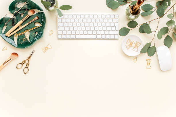 Flat lay home office desk. Female workspace with computer, plate sheet monstera, golden accessories, eucalyptus leaves, on beige background. Top view