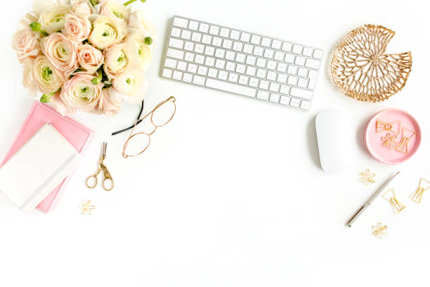 istock Stylized women's home office desk. Workspace with computer, bouquet ranunculus and roses, clipboard on white background. Flat lay. Top view 1276128217