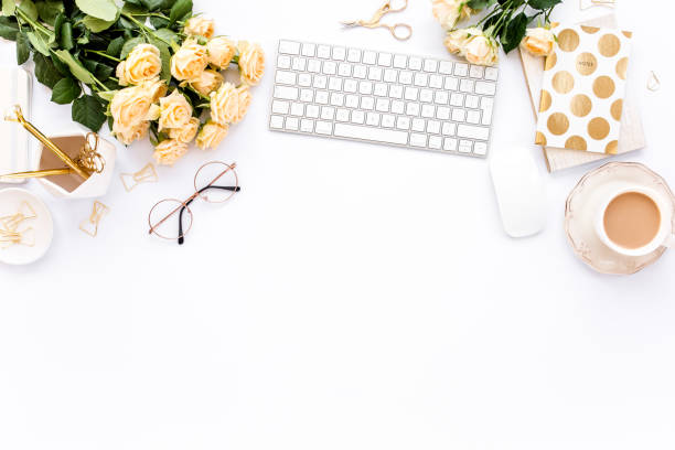 istock Female workspace with computer, roses flowers, golden accessories, diary, laptop, glasses on white background. Flat lay women's office desk. Top view 1276128300