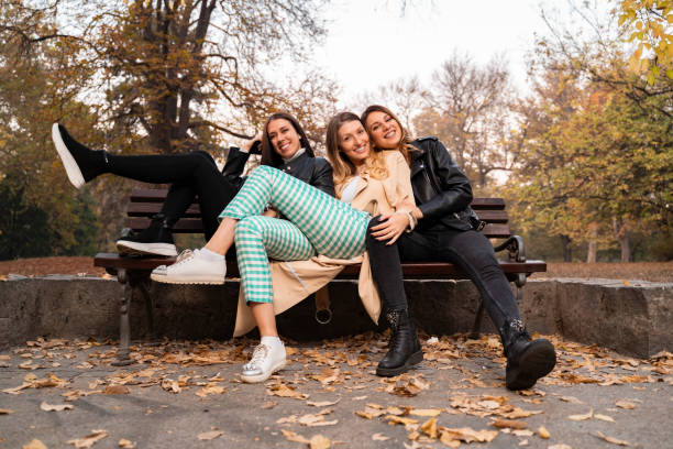 istock Fun positive girls, posing while sitting on park bench 1276134060