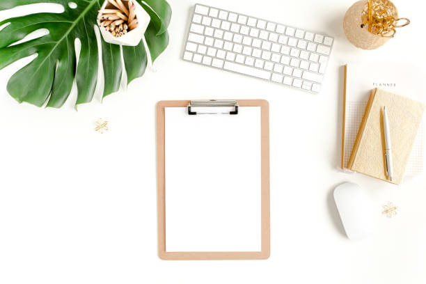 istock Flat lay home office desk. Female workspace with computer, clipboard, tropical palm leaves Monstera, accessories on white background. Top view 1276145282