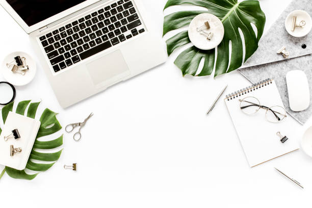 istock Home office workspace mockup with laptop, tropical leaves Monstera, clipboard, notebook and accessories on white background. Flat lay, top view 1276177176