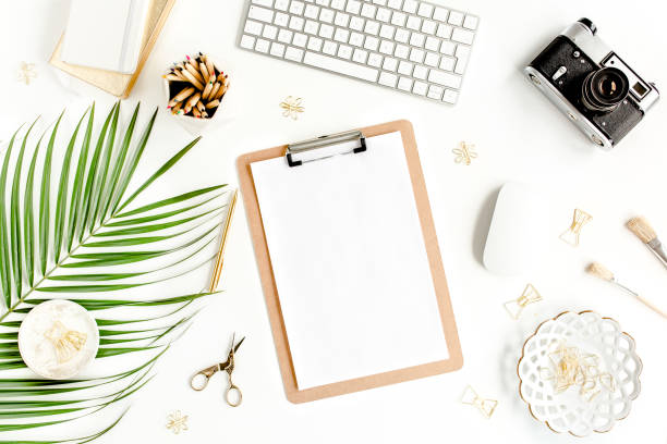 istock Flat lay home office desk. Female workspace with computer, clipboard, tropical palm leaves, accessories on white background. Top view 1276186018