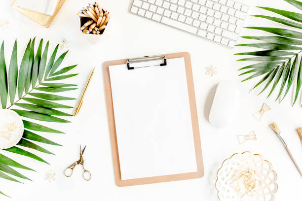 istock Flat lay home office desk. Female workspace with computer, clipboard, tropical palm leaves, accessories on white background. Top view 1276188270