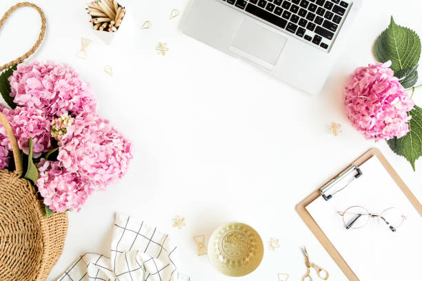 istock Workspace with clipboard, laptop, bouquet hydrangea, accessories on white background. Stylized women's desk. Flat lay. Top view 1276188958