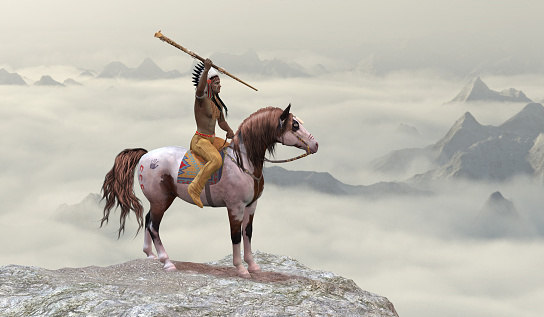 An American Indian in warbonnet rides his war pony to the top of a cliff in the western mountain range.