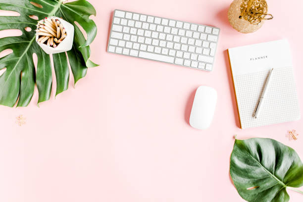 istock Flat lay home office desk. Female workspace with computer, tropical palm leaves Monstera, accessories on pink background. Top view background 1276201260