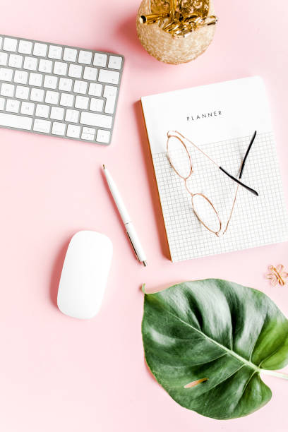 istock Flat lay home office desk. Female workspace with computer, tropical palm leaves Monstera, accessories on pink background. Top view background 1276202137