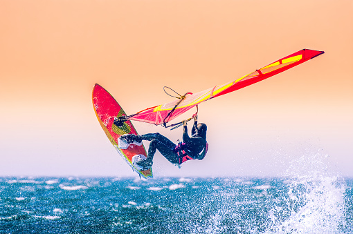 Female kiteboarder holds on to the handle of the kite and overcomes wave after wave on her surfboard