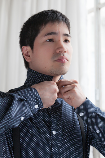 Detail of young asian man dressing up