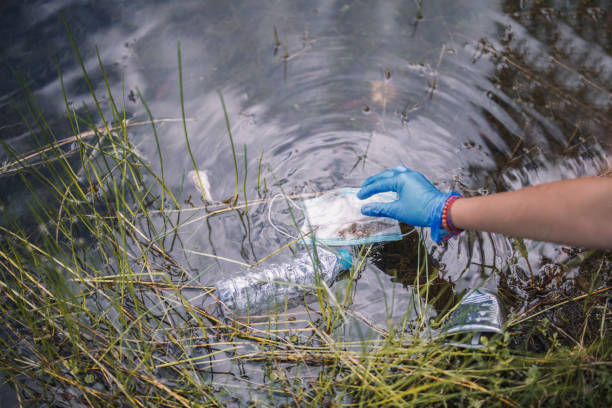 istock Ecology Responsible Person Is Taking Protective Face Mask Leftover In The Nature After Being Used From People 1276258642