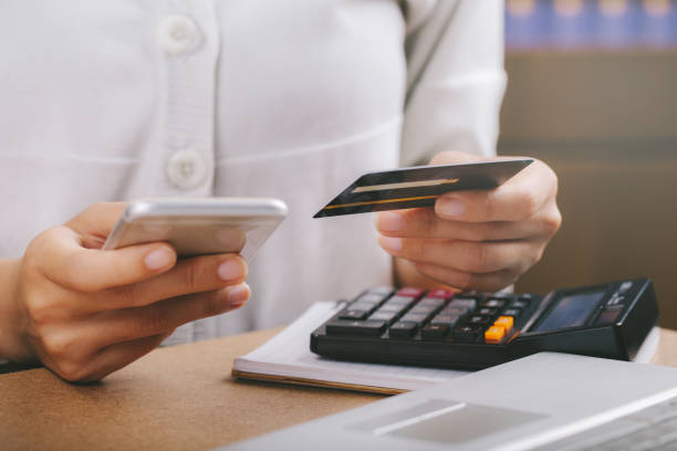 istock Woman holding credit card and using smartphone. Online shopping, e-commerce, internet banking, spending money, working from home concept 1276353700